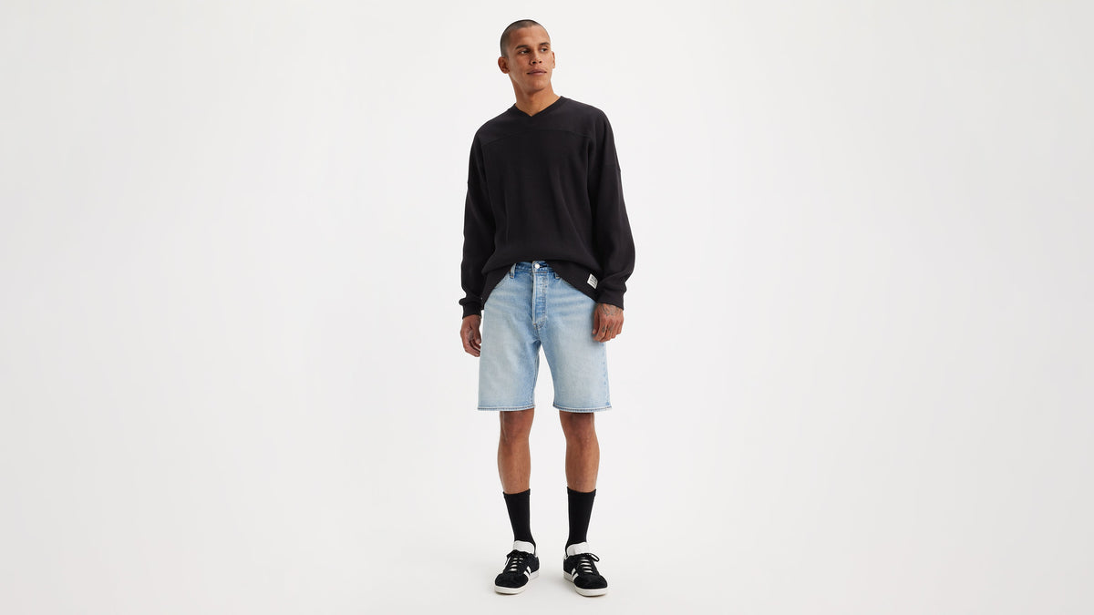 Front view of model wearing Levi’s 501 denim shorts, black sweater, & sneakers