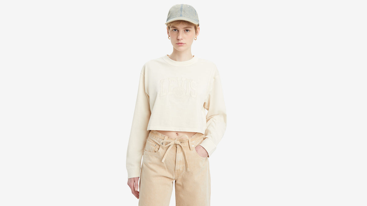 Woman in a cropped Levi’s sweatshirt and beige pants