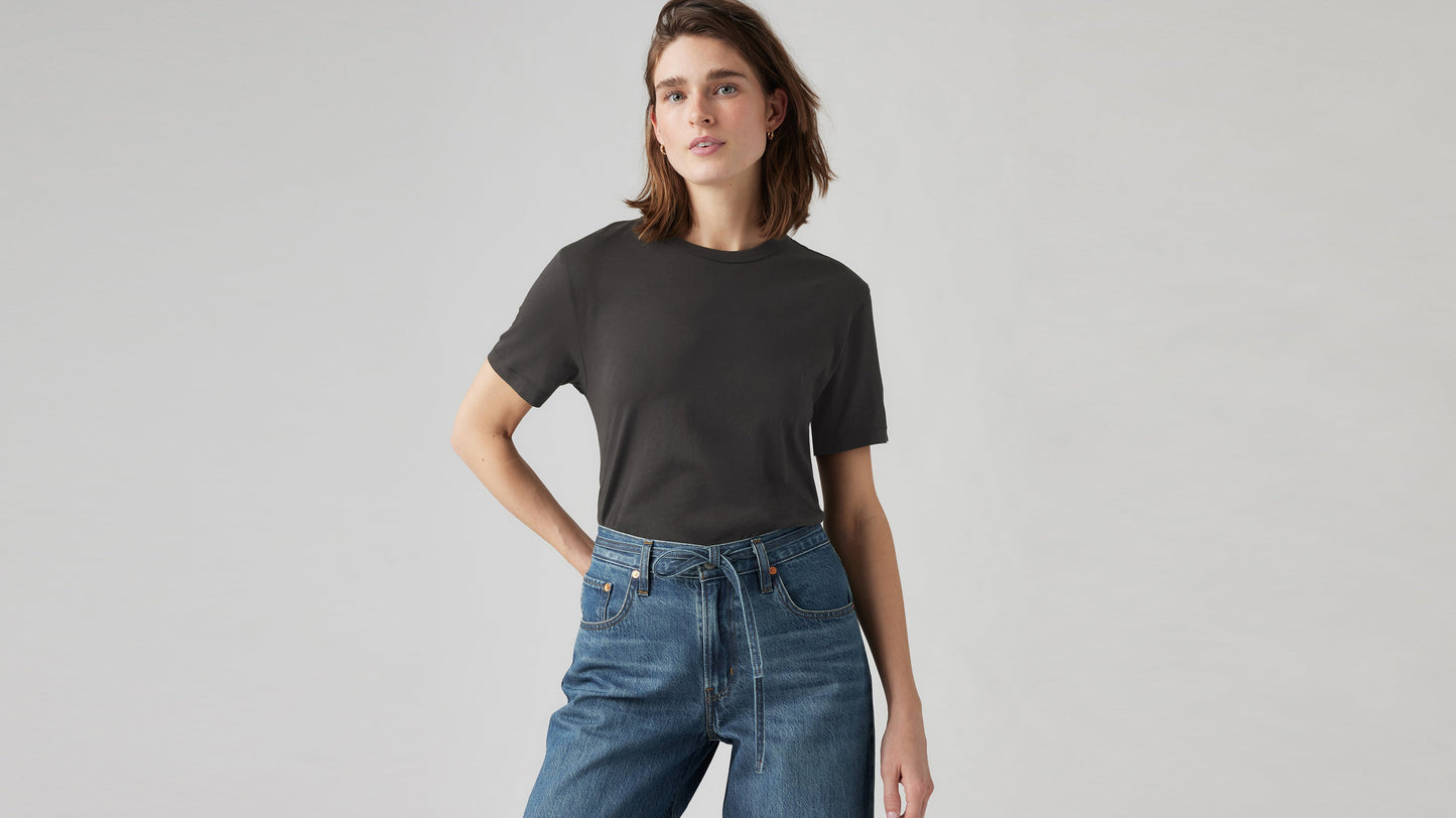 Model wears Levi's black iconic tee tucked into belted high-rise denim jeans