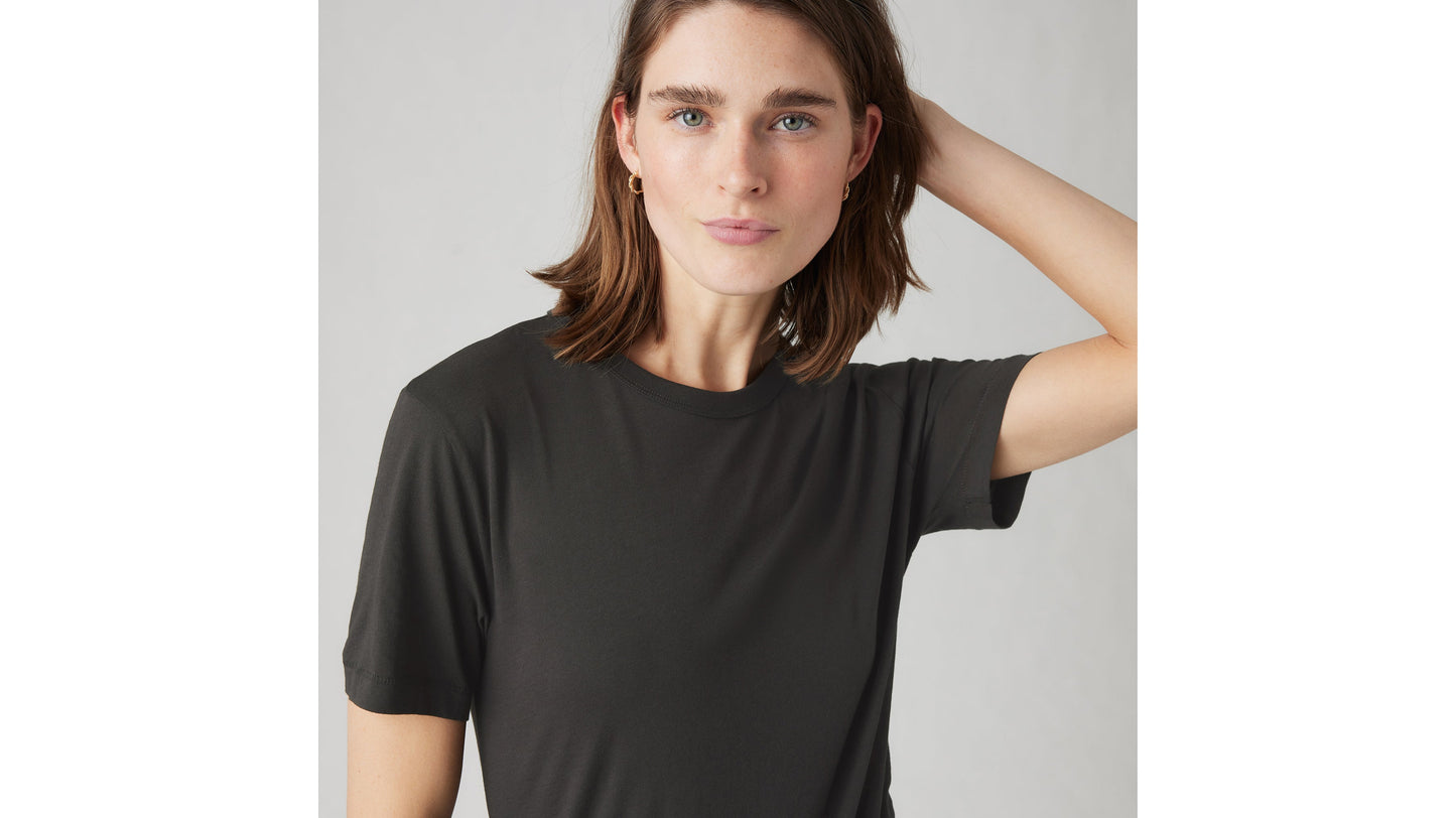 Close-up of woman in black Levi’s iconic tee with hand behind head and soft smile