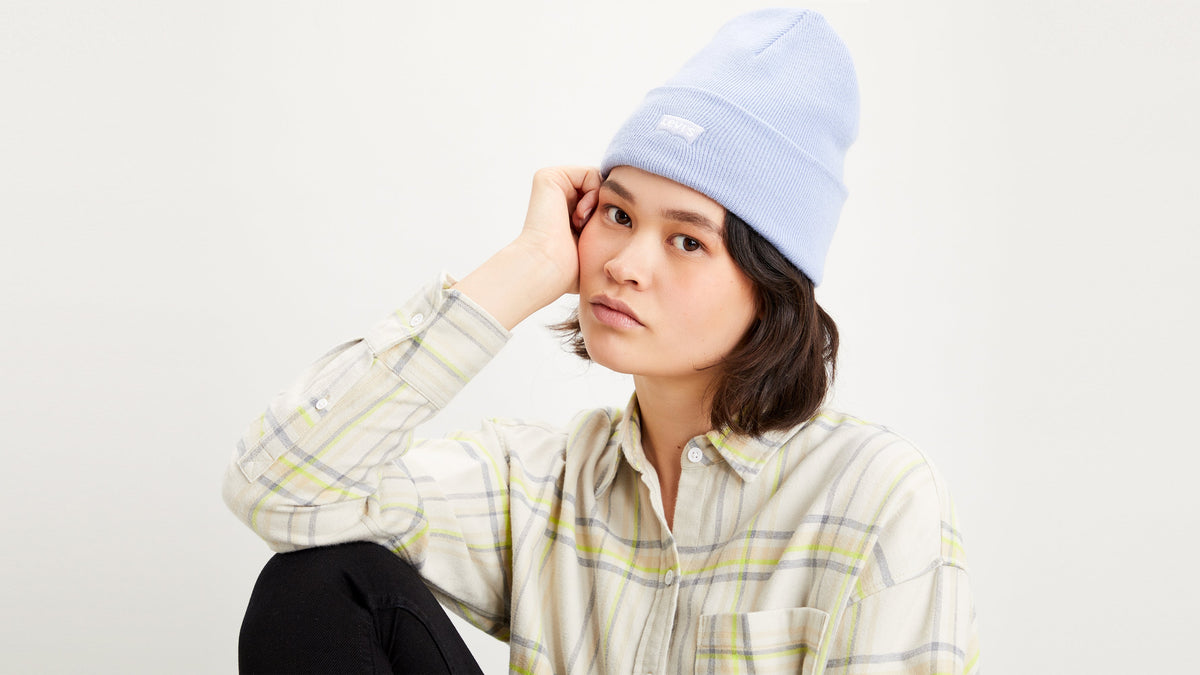 Woman in light blue Levi’s beanie and plaid button-down