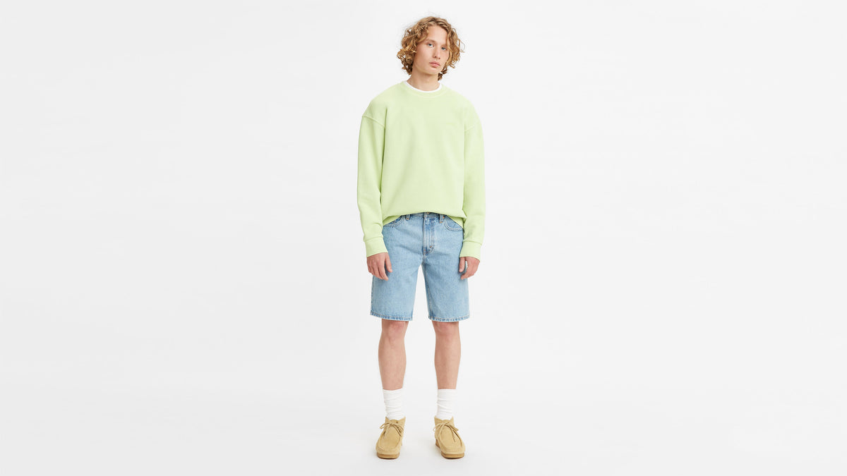 Full-body shot of model in a green sweatshirt, Levi's Men's 405 shorts, & sneakers