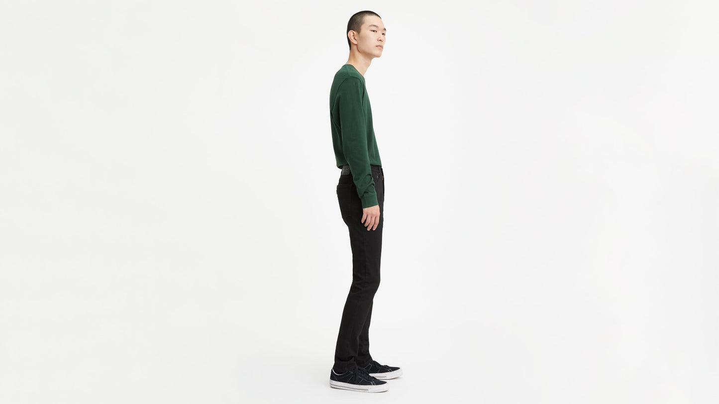 Back shot of a man in black Levi’s skinny jeans, green sweatshirt, & black sneakers