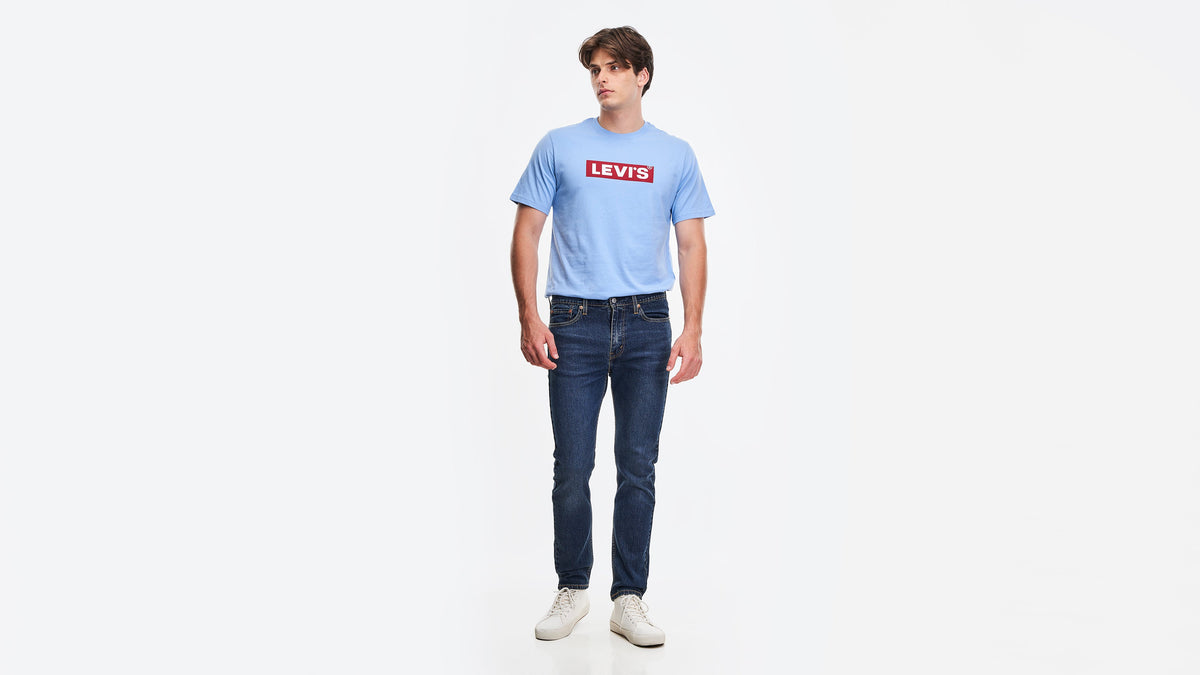 Man wearing Dark Indigo Levi's 510 Skinny Jeans, blue tee & white sneakers, front view