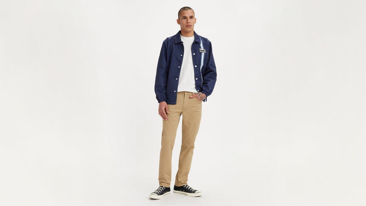 Front view of a model wearing beige Levi’s 511 jeans, white tee, and navy jacket