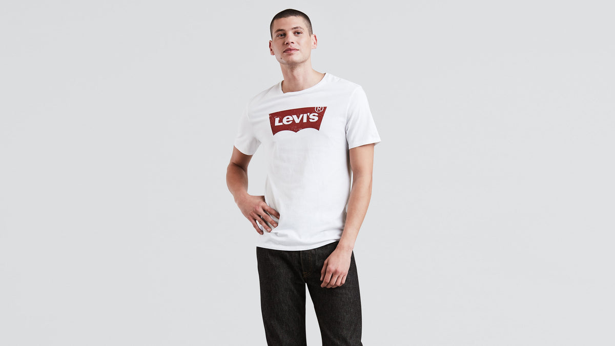 Man wearing a white Levi’s graphic tee with dark black jeans, front view