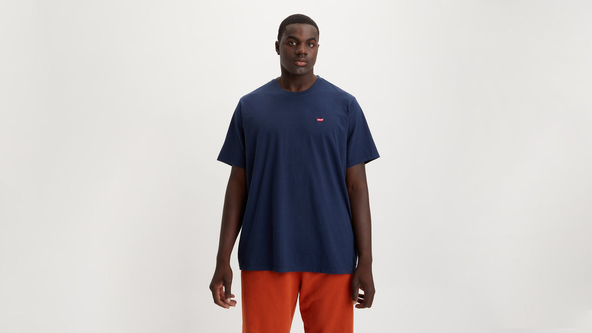 Man wearing a navy Levi’s t-shirt with a red tab logo & orange sweatpants, front view