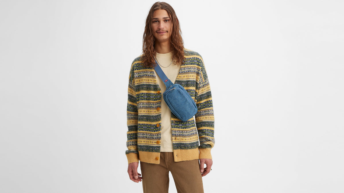 Front view of man in patterned cardigan and crossbody blue Levi’s pouch