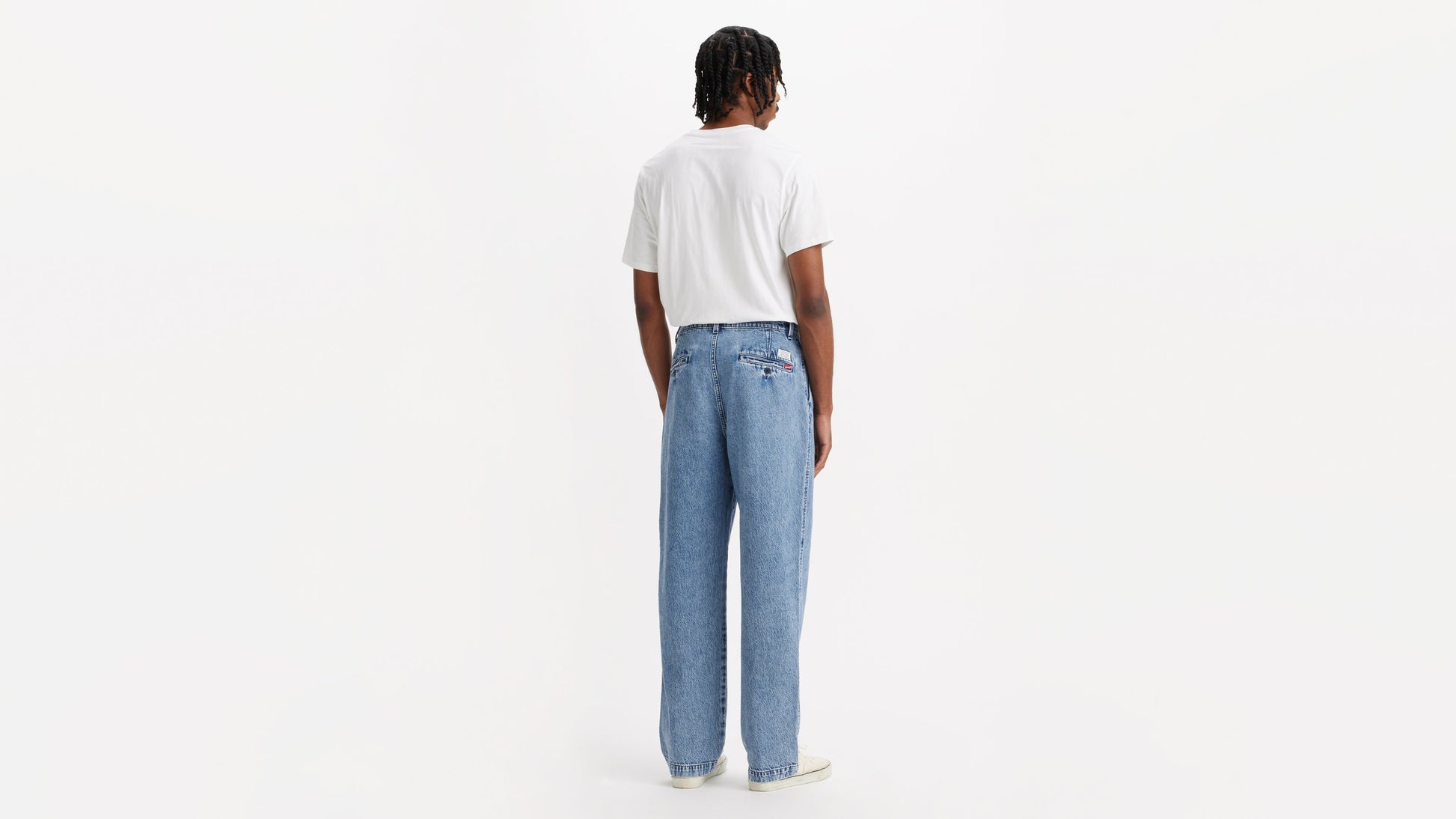 Back view of man in chino loose straight pants and plain tee, hands by his sides
