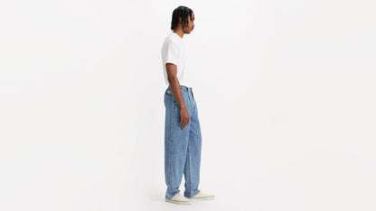 Side view of man in chino loose straight pants and plain tee, hands by his sides