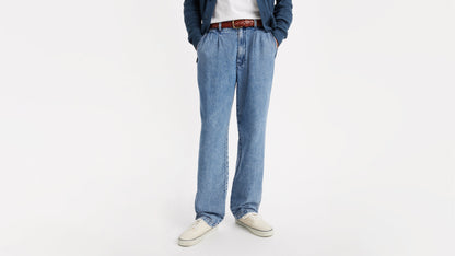 Close-up of blue chino loose straight pants, brown belt, and off-white canvas shoes