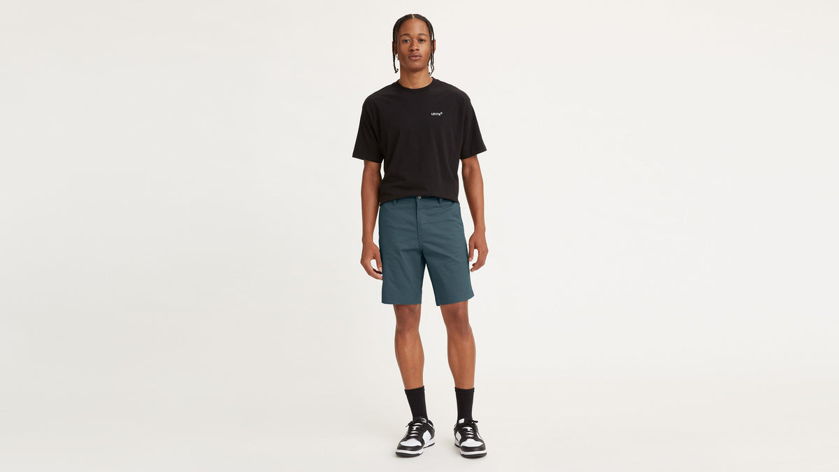 Front view of Levi’s Chino Shorts in deep teal green with black T-shirt, socks, & sneakers