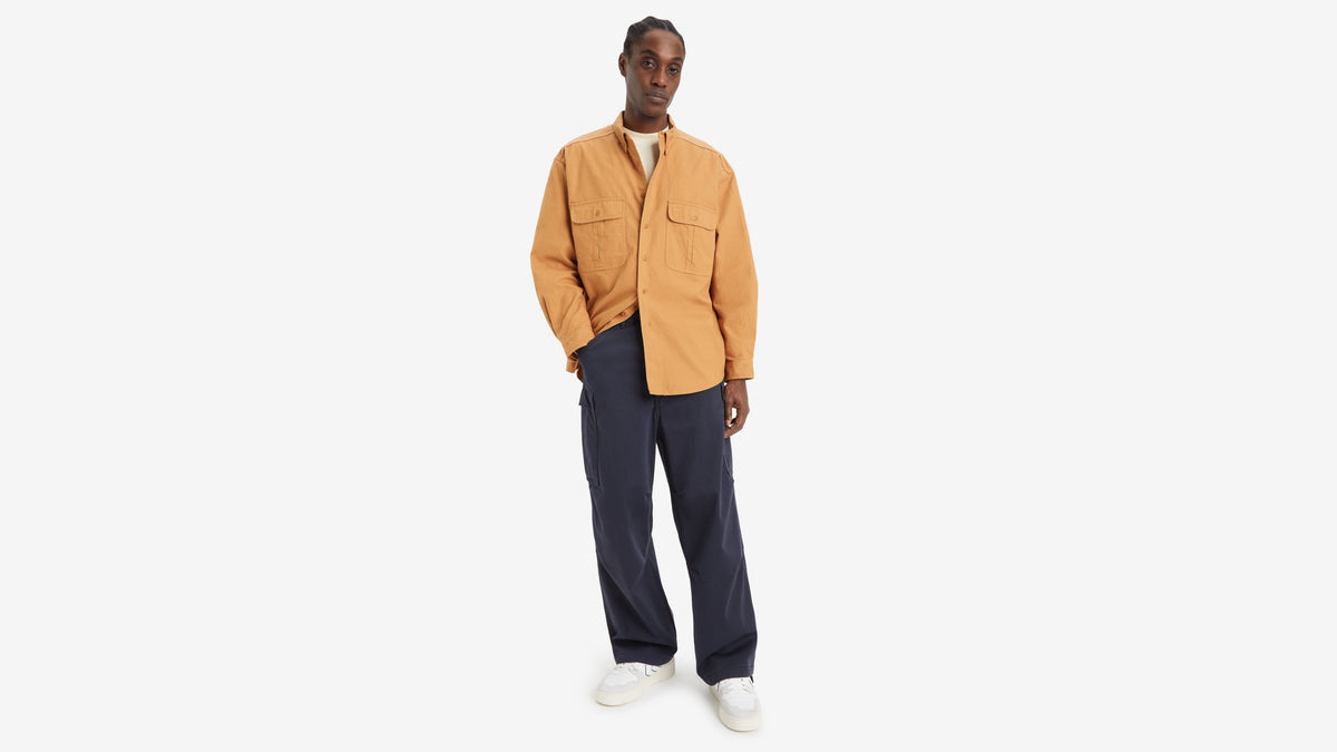 Front view of model in tan shirt, navy loose cargo pants, and white sneakers