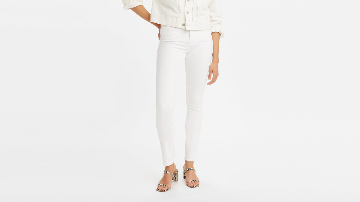 Woman in front view wearing Levi's white skinny jeans and snake-print block heel sandals