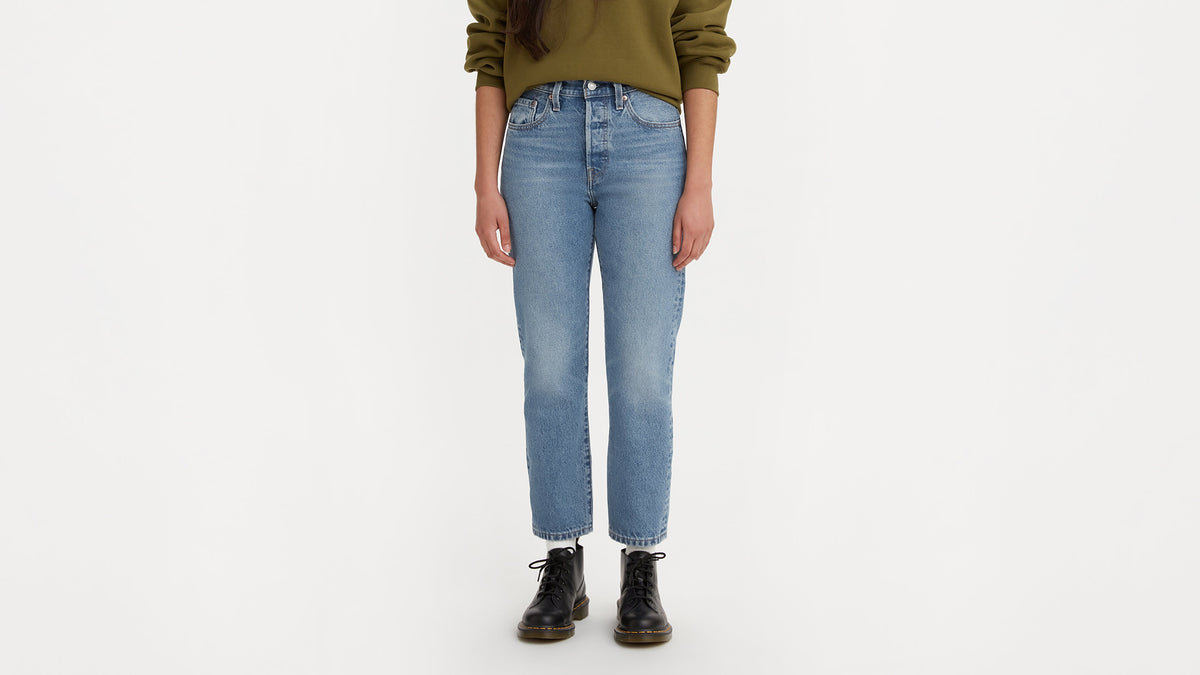 Front view of woman in Levi's 501 cropped jeans, green sweatshirt, & black lace-up boots