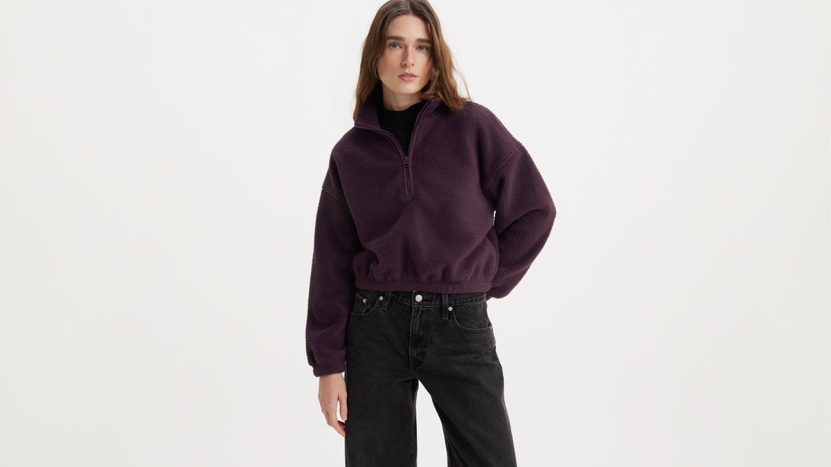 Woman in plum Levi’s quarter-zip sweater and black jeans