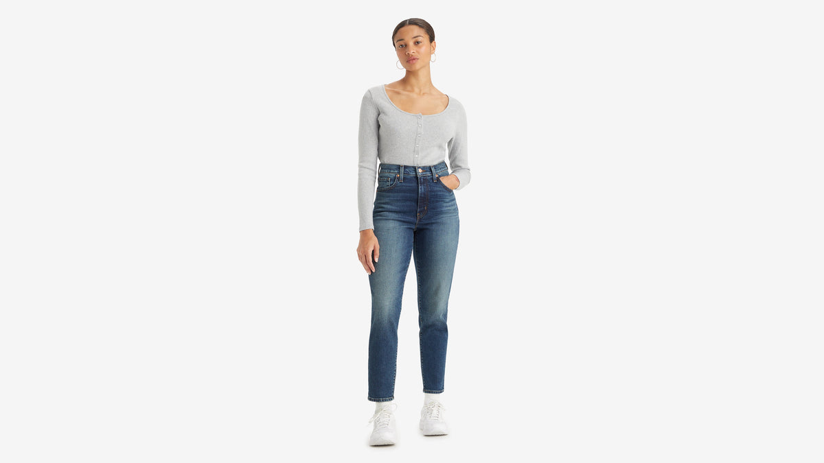 Front view of a woman in long-sleeve top tucked in high-waisted mom jeans
