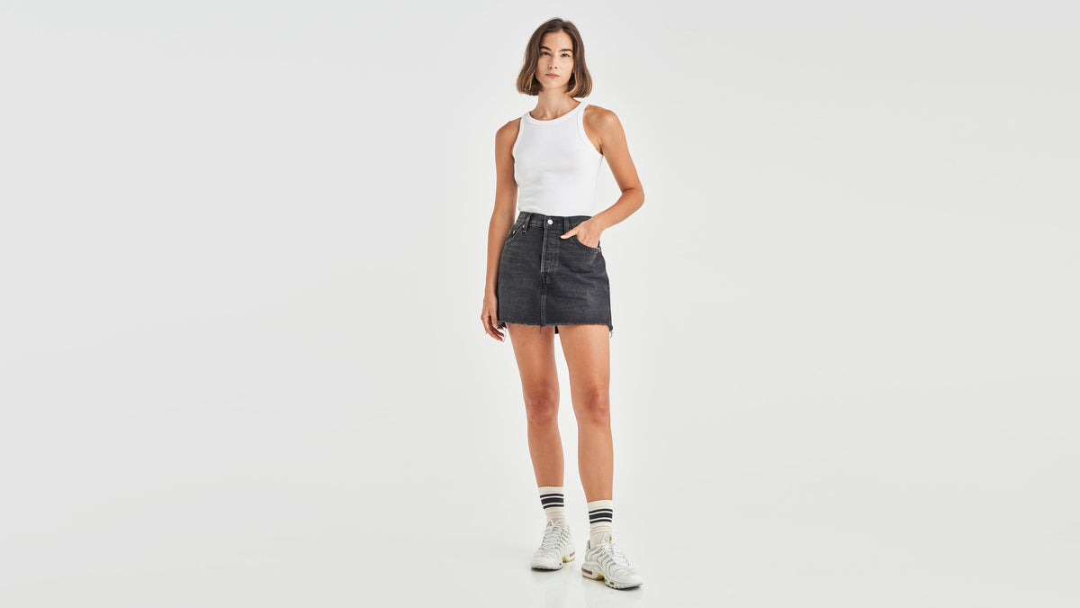 Front view of woman in black Levi's icon skirt with white tank top and sneakers