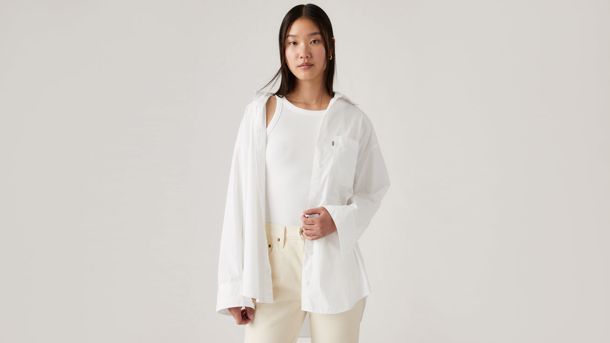 Front-facing view of woman in Levi's white Lola shirt layered over tank and trousers