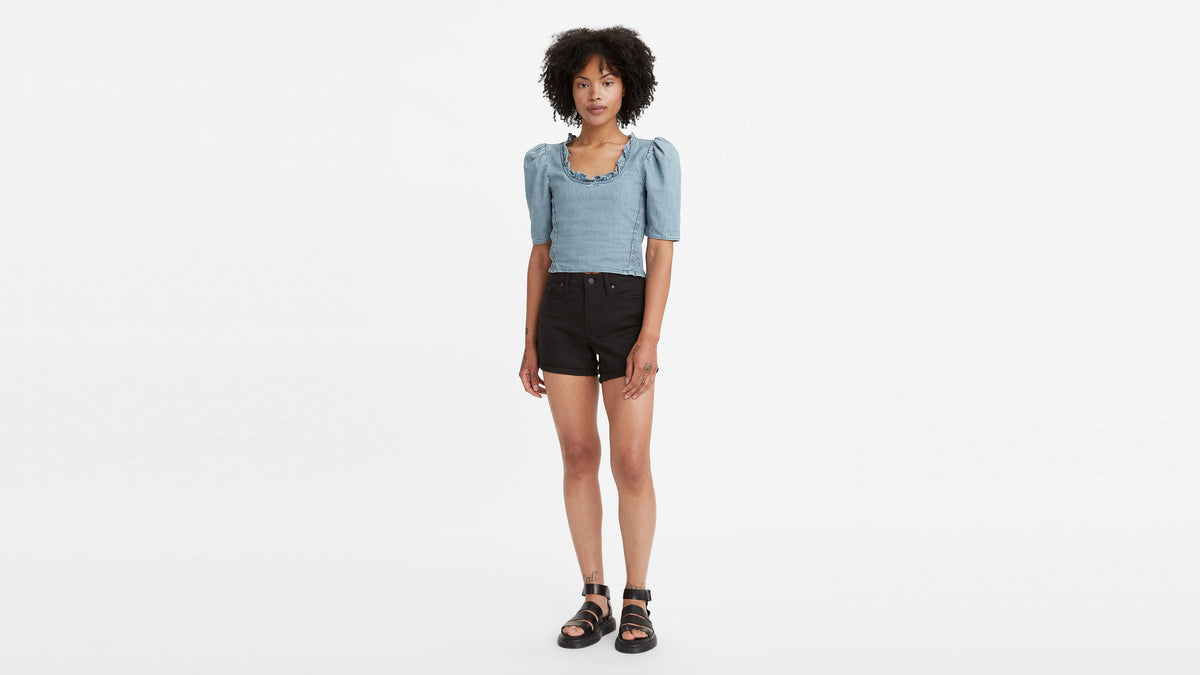 Woman in black mid-length shorts & blue top with puff sleeves