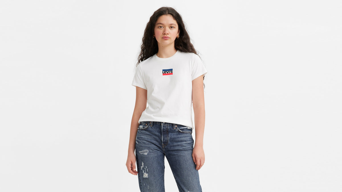 Front view of model wearing Levi’s white perfect tee with red-navy logo with ripped jeans