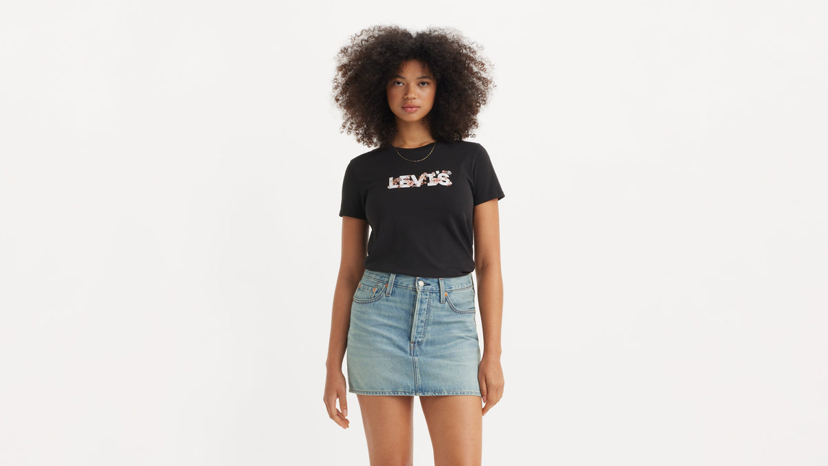 Front view of a woman in black Levi's tee tucked in mini denim skirt