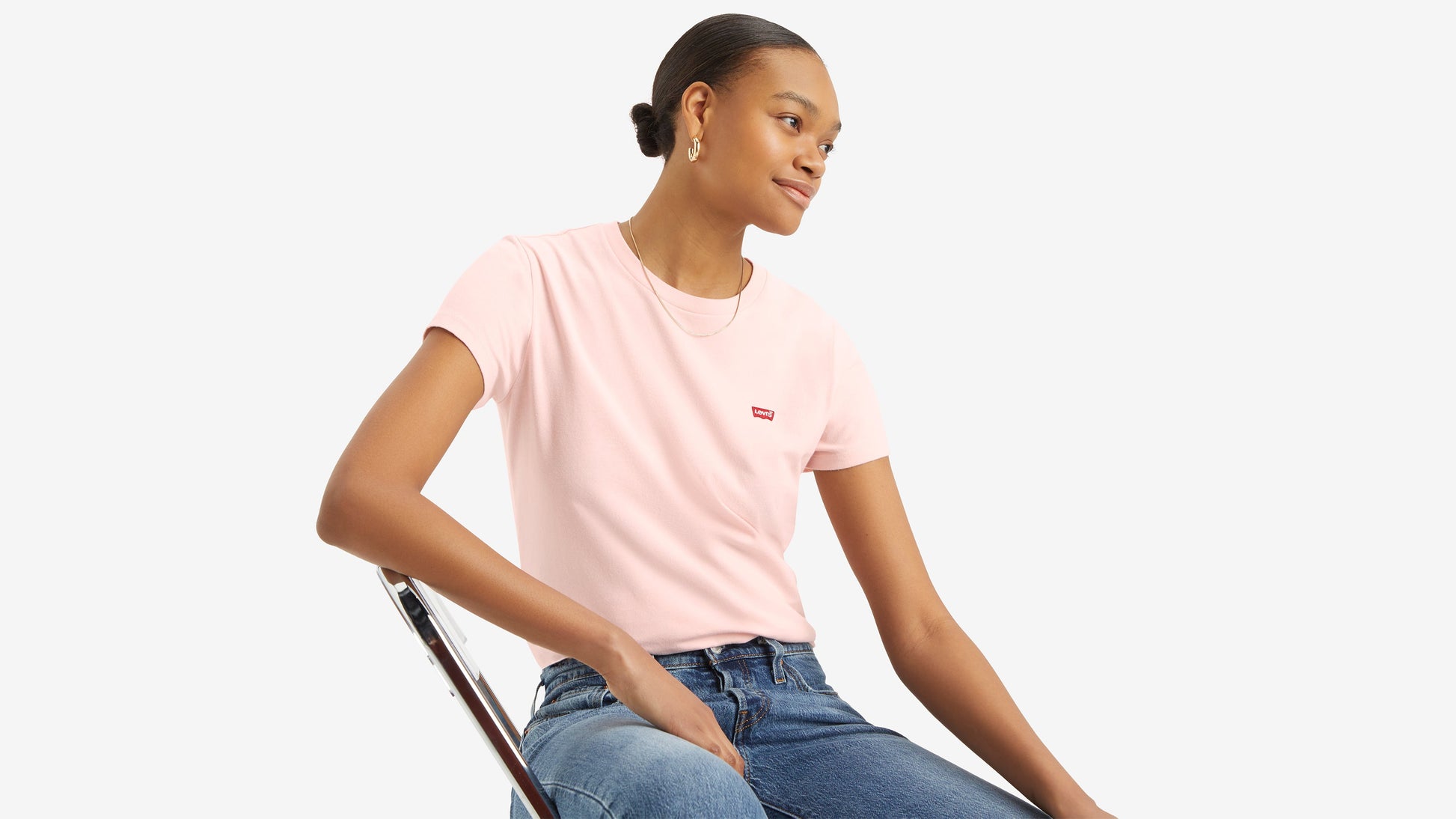 Model seated in a light pink Levi’s t-shirt and blue jeans