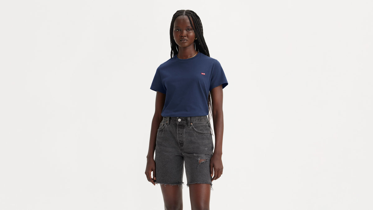 Front view of woman in navy Levi’s tee tucked in black distressed denim shorts